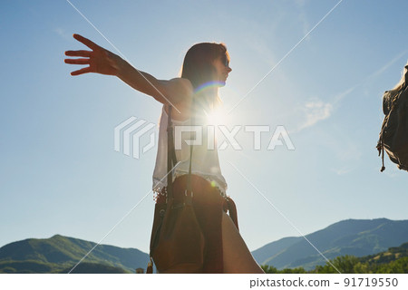 Carefree young woman balancing and walking during a hike in nature with a friend. Young woman enjoying a hike in nature in with a friend. Happy young woman balancing during hike in nature with friend 91719550