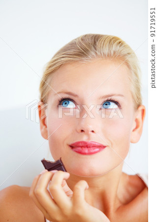 Mmm, this is heavenly. Smiling young woman enjoying a delicious piece of chocolate. Mmm, this is heavenly. Smiling young woman enjoying a delicious piece of chocolate. 91719551