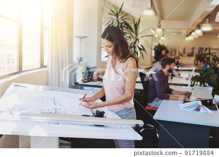Working on a new building plan. Cropped shot of a young architect working on her drafting table. Working on a new building plan. Cropped shot of a young architect working on her drafting table. 91719884