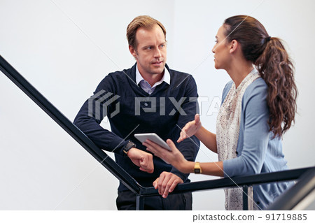 Making decision on the go. Shot of two colleagues using a digital tablet while standing in a stairwell. 91719885
