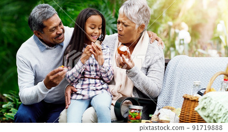 We always have healthy treats for her. Shot of a cheerful little girl sitting down on a bench with her grandparents at the park. We always have healthy treats for her. Shot of a cheerful little girl sitting down on a bench with her grandparents at the park. 91719888