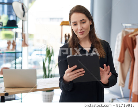 Her small business is big online too. Shot of a young business owner using a digital tablet in her clothing store. 91719913