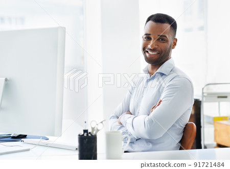 Hes confident in his career. A handsome young african american businessman working at his desk. Hes confident in his career. A handsome young african american businessman working at his desk. 91721484