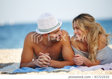 Holiday romance. Shot of a happy young couple lying on the beach. 91722010