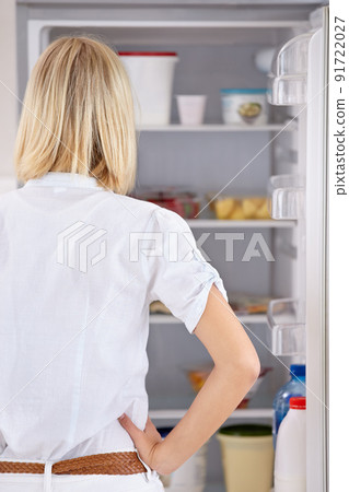 What to eat. Rearview of a young woman looking in her fridge. 91722027