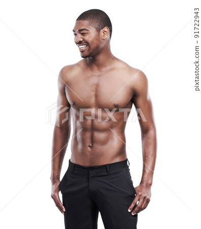 Hes got the body of an athlete. A handsome young man standing shirtless in the studio. 91722943