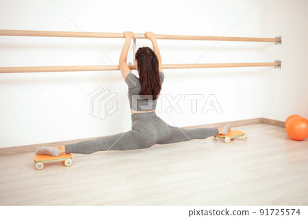 woman makes transverse twine with her feet on special carts with wheels. woman makes transverse twine with her feet on special carts with wheels. 91725574