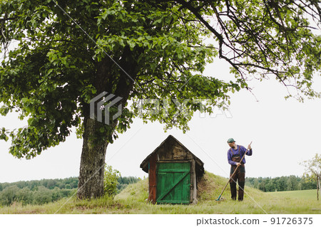 Man working in the garden with rake in a sunny day. Farmer working in the backyard 91726375