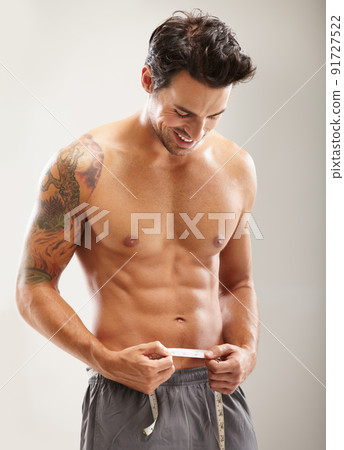 Proud of his rock hard abs. A hunky young man measuring his stomach. Proud of his rock hard abs. A hunky young man measuring his stomach. 91727522