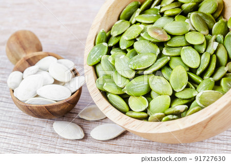The Organic pumpkin seeds in wooden bowl on wooden table. 91727630