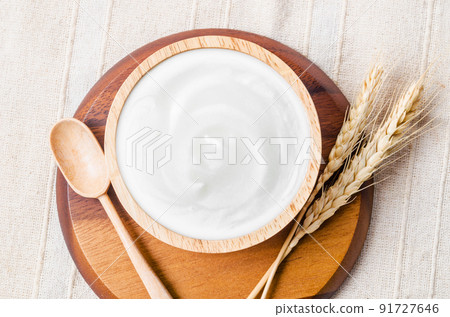 Greek yogurt in a wooden bowl and dry barley on table. 91727646