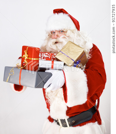 Bringing you some Christmas magic. Santa Claus holding a pile of wrapped christmas gifts - portrait. Bringing you some Christmas magic. Santa Claus holding a pile of wrapped christmas gifts - portrait. 91727935