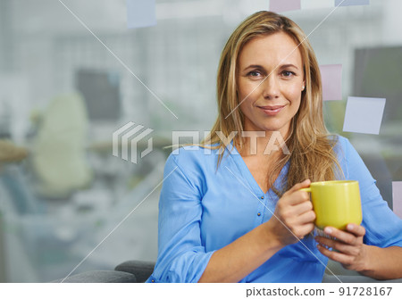 I can't work without my coffee. Attractive blonde female employee having her coffee break. 91728167