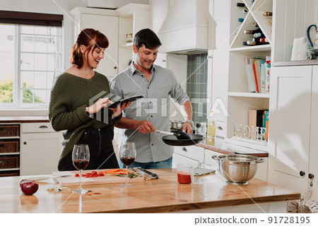 Everything has to look perfect for our blog. Shot of a couple using a digital tablet while cooking at home. 91728195