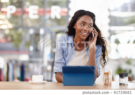 Im waiting for you at the coffee shop. Cropped shot of an attractive woman sitting in a coffee shop using a cellphone and tablet. 91729081