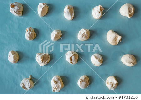 Homemade french milk-colored meringues on blue paper Homemade french milk-colored meringues on blue paper 91731216