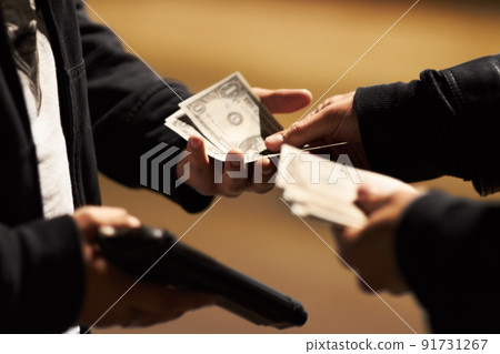 Sealing the deal. Hands holding cash and a gun passing money between them. Sealing the deal. Hands holding cash and a gun passing money between them. 91731267
