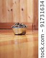 Metal bowl with dry pet food stands on the wooden floor 91731634