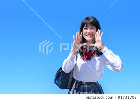 A high school girl who supports her, a woman who calls with her hand in her mouth, a beautiful blue sky back 91731702