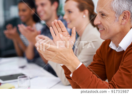 Hes proud of his young up and comers. Cropped shot of a handsome mature businessman sitting amongst his coworkers. Hes proud of his young up and comers. Cropped shot of a handsome mature businessman sitting amongst his coworkers. 91731987