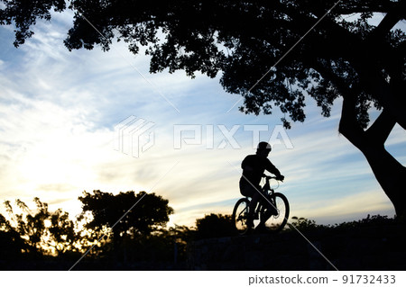 Ride on.... Silhouette shot of a man riding his bike at dusk. Ride on.... Silhouette shot of a man riding his bike at dusk. 91732433
