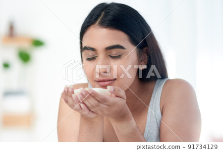 Im about to smell amazing. Shot of young woman smelling some skincare product. Im about to smell amazing. Shot of young woman smelling some skincare product. 91734129