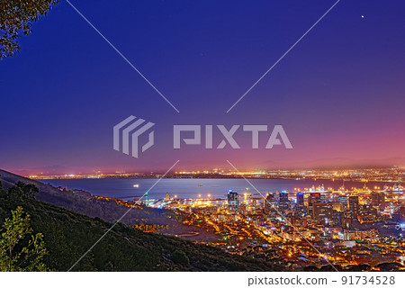 Signal Hill in Cape Town South Africa with copyspace against dark night sky background and the view of a coastal city. Scenic panoramic landscape of lights illuminating an urban skyline along the sea 91734528