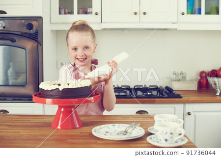 I made this cake all by myself. Cute little girl icing a cake in the kitchen. 91736044