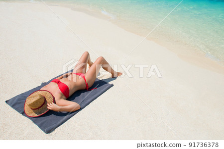 shot of a woman sunbathing on her towel on the beach shot of a woman sunbathing on her towel on the beach 91736378