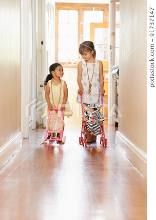 Acting like a mother..... Full-length shot of two little girls pushing prams. Acting like a mother..... Full-length shot of two little girls pushing prams. 91737147