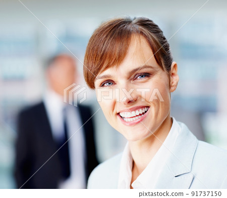 Happy female executive with colleagues in background. Focus on happy female executive with team behind her. 91737150