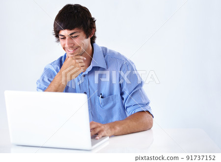 Browsing the web. Shot of a smiling young businessman working at a laptop. Browsing the web. Shot of a smiling young businessman working at a laptop. 91737152