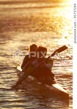 Out on the water. A shot of two young people on a kayak at sunset. Out on the water. A shot of two young people on a kayak at sunset. 91737264