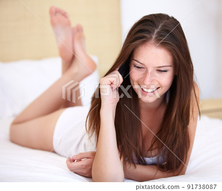 What time is it there. A gorgeous young woman talking on the phone while lying on her bed. 91738087