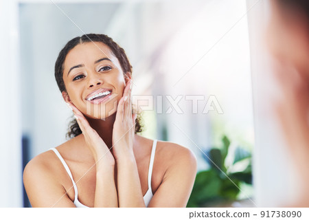 Skin that looks good, makes you feel good. Cropped shot of an attractive young woman touching her face during her morning routine. 91738090