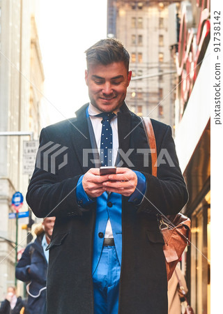 Standing by myself in a different world. Shot of a cheerful young man texting on his cellphone while standing in the busy streets of the city during the day. Standing by myself in a different world. Shot of a cheerful young man texting on his cellphone while standing in the busy streets of the city during the day. 91738142
