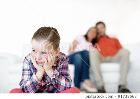 I hate timeout. A little girl sits and sulks while her parents in the background. 91738668
