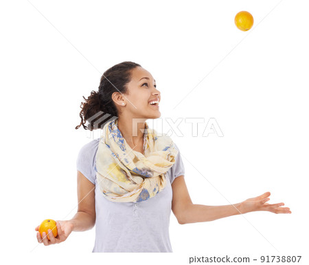 Shes got her eye on balancing a healthy diet. Young woman smiling while juggling some fresh oranges. 91738807