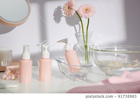Front view of cosmetic jar in white bathroom with glassware and flower for cosmetic advertising , lifestyle content Front view of cosmetic jar in white bathroom with glassware and flower for cosmetic advertising , lifestyle content 91738983