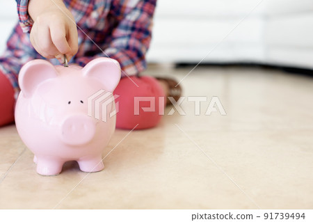Start saving early-copyspace. Horizontal shot of a little girls hand putting coins in a piggybank. Start saving early-copyspace. Horizontal shot of a little girls hand putting coins in a piggybank. 91739494
