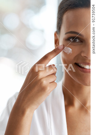Her daily skincare routine. Closeup portrait of a gorgeous young woman applying moisturizer to her skin. Her daily skincare routine. Closeup portrait of a gorgeous young woman applying moisturizer to her skin. 91739504