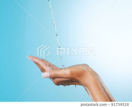 Moisture rejuvenates the skin. Cropped shot of an unrecognisable woman cupping her hands to catch water against a blue background in the studio. 91739528