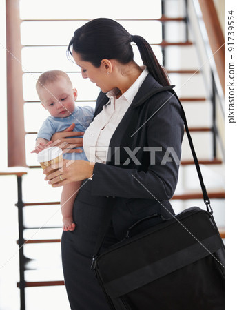 Mommys off to the office. Working mother standing with her briefcase holding a baby. Mommys off to the office. Working mother standing with her briefcase holding a baby. 91739554