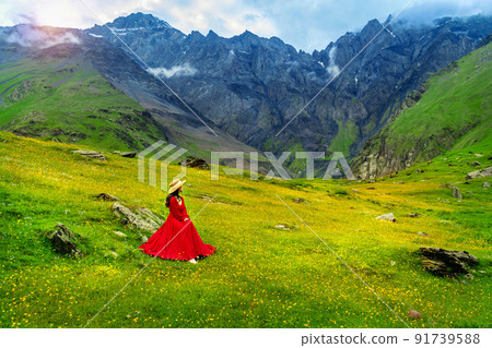 Tourist enjoy view of green pasture and flowers near Elia mountain in Georgia. 91739588