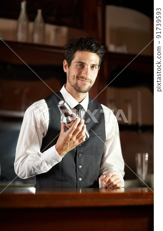 Master of his domain. Portrait of a handsome young bartender mixing a cocktail for a customer. Master of his domain. Portrait of a handsome young bartender mixing a cocktail for a customer. 91739593