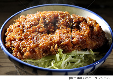 Hot sauce and bowl with cutlet entwined with plenty of sauce on top of shredded cabbage 91739879