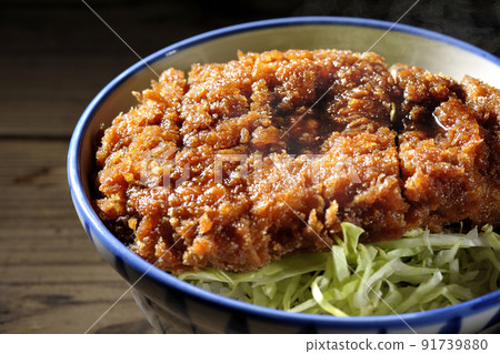 Hot sauce and bowl with cutlet entwined with plenty of sauce on top of shredded cabbage 91739880