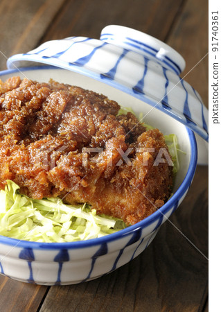 Hot sauce and bowl with cutlet entwined with plenty of sauce on top of shredded cabbage 91740361