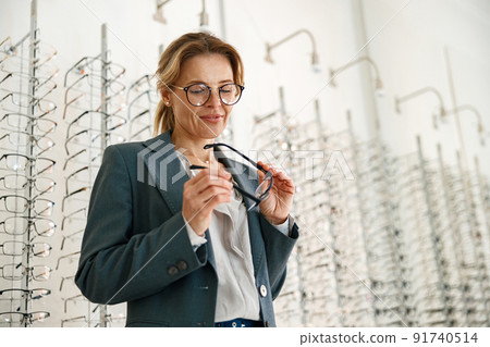 Businesswoman chooses a spectacle frame in an optician's shop 91740514