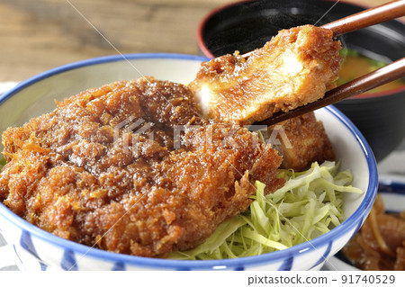 Hot sauce with a cutlet entwined with plenty of sauce on top of shredded cabbage, katsudon, miso soup, and pickles 91740529